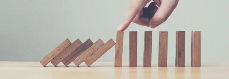 finger stopping blocks from falling over to represent recession-proofing your business