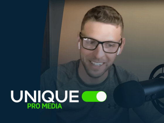 Smiling man with glasses talking into a microphone.